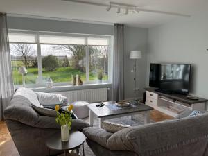 a living room with two couches and a television at Mariannes Hues Wohnung 1 in Borgsum