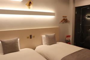 um quarto com 2 camas e lençóis brancos em ホテル SHUNJU Dosse 1日1組様限定 em Quioto