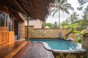 a swimming pool with a wooden deck next to a house at Pondok Sebatu Eco Lodge in Tegalalang