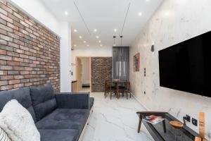 een woonkamer met een bank en een tv aan een bakstenen muur bij Affogato by halu!: Bright and modern apartment in Thessaloniki