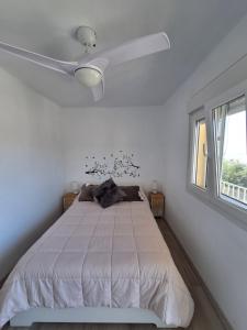 1 dormitorio blanco con 1 cama y ventilador de techo en Casa mirador Perea, en Málaga