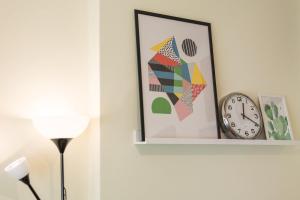 a clock on a wall with a picture and a lamp at GuestReady - Sweet & Relax Flat in Porto