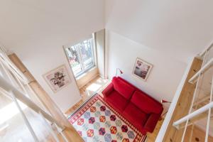 een rode bank in een kamer met een tapijt bij GuestReady - Belas Artes Duplex in Porto