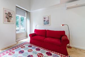 een rode bank in een woonkamer met een tapijt bij GuestReady - Belas Artes Duplex in Porto