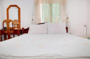 1 dormitorio con 1 cama blanca con espejo y silla en Blue Sea 01 Hotel, en Nha Trang