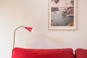 een rode bank met een lamp en een foto aan de muur bij GuestReady - Belas Artes Duplex in Porto