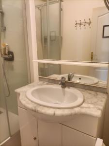 un bagno con un lavandino bianco e uno specchio di Le Cheval Blanc La Chartre sur le Loir a La Chartre-sur-le-Loir