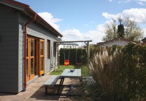 um quintal com uma mesa de piquenique e uma casa em Villa Emilia - Gemütliches kinderfreundliches Blockhaus mit umzäuntem Garten em Sint Annaland