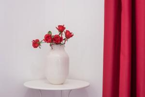 a white vase with red flowers sitting on a table at GuestReady - Beautiful Plateau in Porto
