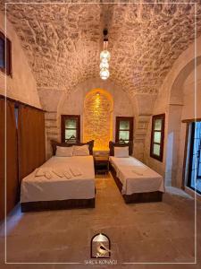 1 dormitorio con 2 camas y pared de piedra en Serce Konagi, en Sanlıurfa