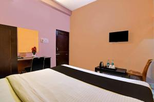 a bedroom with a bed and a desk and a television at Chilika Residency in Bhubaneshwar