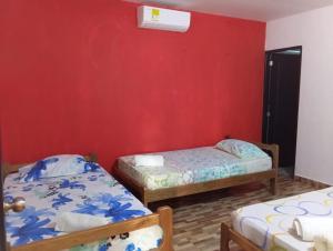 2 camas en una habitación con una pared roja en Villa del Carmen e hijos, en San Antero