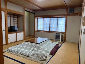 a room with a bed and a table and two windows at irodori in Matsumoto