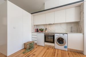 a kitchen with white cabinets and a washing machine at GuestReady - Coral Apartment in Porto