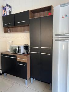 a kitchen with black cabinets and a refrigerator at Casa refúgio de paz in Cabo Frio