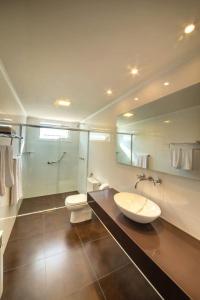 a bathroom with a sink and a toilet and a mirror at Grande Hotel Canela in Canela