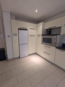 a kitchen with white cabinets and a refrigerator at Large 6 Bedroom house in Hendon in Hendon