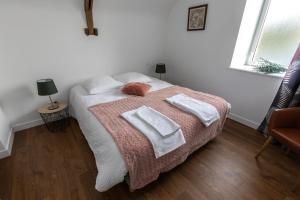 1 dormitorio con 1 cama con 2 toallas en Les gîtes du Haut Pin, en Calorguen