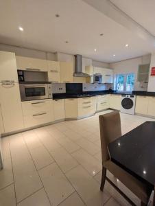 a large white kitchen with a table and a chair at Large 6 Bedroom house in Hendon in Hendon