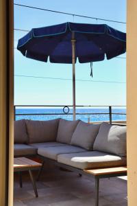 kanapę z niebieskim parasolem na balkonie w obiekcie B&B Acqua di Mare w mieście Bordighera