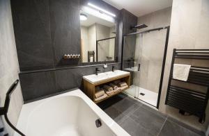 a bathroom with a tub and a sink and a mirror at Hotel Kras in Jedovnice