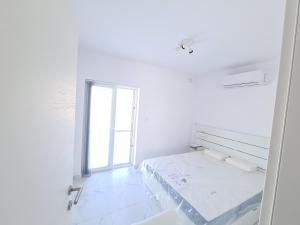Cette chambre blanche dispose d'un lit et d'une fenêtre. dans l'établissement Top Floor with terrace and 5 mins walk to centre, à Marsaskala