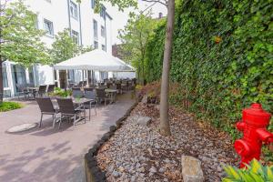 a red fire hydrant next to a hedge with tables and chairs at Dorint Hotel Würzburg in Würzburg