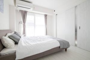 ein weißes Schlafzimmer mit einem Bett und einem Fenster in der Unterkunft オーシャンズスイート 東京ディズニーリゾートコージーバルコニー302 in Tokio