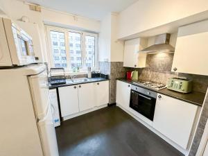 a kitchen with white cabinets and a sink at Vibrant 3BR flat near Finsbury Park in London