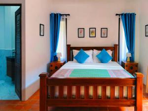 a bedroom with a wooden bed with blue curtains at 4 Bed Villa Private Pool and BBQ Jomtien Beach in Jomtien Beach