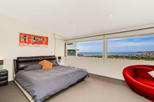 Deewhy的住宿－Pure Magical Views - Ocean Views，一间卧室配有一张床和一张红色椅子