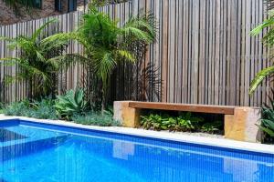 a swimming pool with a wooden bench next to a fence at Freshwater Villa - Seconds to the Beach in Freshwater