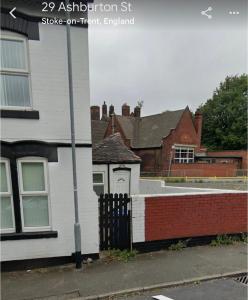una casa blanca con una puerta y una valla de ladrillo en 29 ASHBURTON STREET en Stoke on Trent