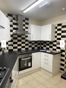 a kitchen with white cabinets and black and white checkered walls at 29 ASHBURTON STREET in Stoke on Trent