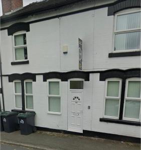 un edificio blanco con una puerta y dos cubos de basura en 29 ASHBURTON STREET en Stoke on Trent