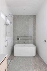 a white bathroom with a tub and a shower at Chic Coastal Retreat Prime Setting in Curl Curl