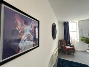 a tv hanging on a wall with a picture of a dog at Land Of Green Ginger Apartment- City Centre in Hull