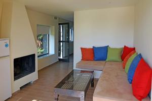 een woonkamer met een bank en kleurrijke kussens bij Holiday Village - Swimming pool apartments in Kamena Vourla