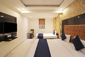 a hotel room with a bed and a flat screen tv at The Rose Manor By Iconic Delhi International Airport in New Delhi