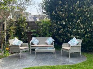 3 sillas de mimbre con almohadas en el patio en Rooms in Hadleigh,Essex en Hadleigh