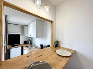 una cocina con una mesa de madera con copas de vino. en LE BRASILIA - Terrasse & Parking, en Mont-de-Marsan