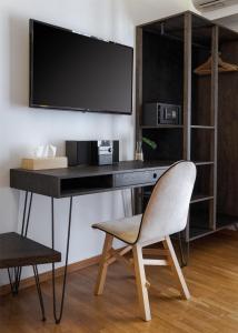 a desk with a chair and a television on a wall at Acropolis Unique Residence in Athens