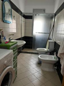 y baño con aseo, lavabo y lavadora. en Sea View Apartment Lungo Mare, en Vlorë