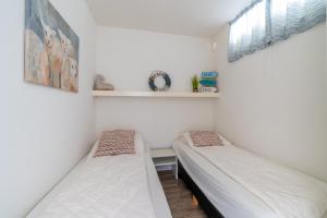 2 camas en una habitación con paredes blancas y ventana en Appartementencomplex Juliana 88, en De Koog