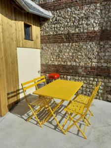 una mesa amarilla y dos sillas junto a un edificio en Le Manège, en Thiétreville