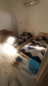 two beds in a room with shoes on the floor at Budget Muscat Room in Seeb