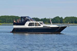 a boat in the water with people on it at Kuhnle-Tours Hafendorf Müritz in Rechlin