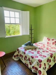 Casa de dois quartos para 6 pessoas-Casa das Flores في أورو بريتو: غرفة نوم خضراء بها سرير ونافذة