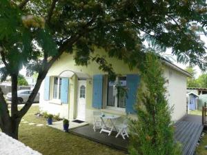 een klein huis met blauwe luiken en een tafel bij Maison Le Grand-Village-Plage, 3 pièces, 4 personnes - FR-1-246A-314 in Grand-Village-Plage
