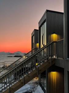 a building on the beach with the sunset in the background at Henningsvær Lofoten new apartment in Henningsvær